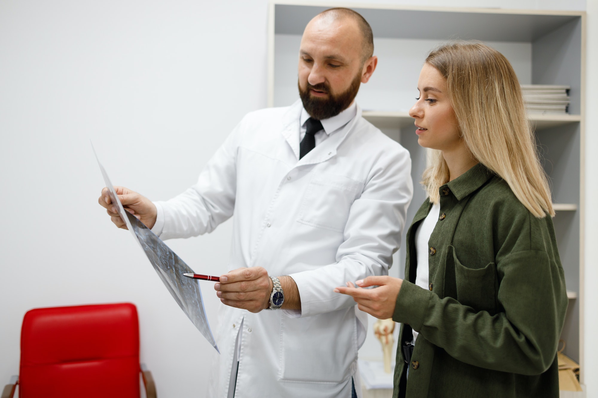 Male doctor explaining xray report to young female patient