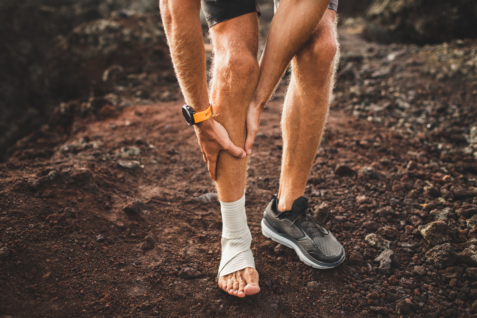 Male runner holding injured leg close-up and suffering with pain. Leg injury. Sprain ligament