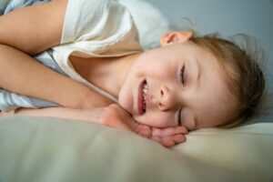 Cute little girl sleeping and grinding teeth in dreams, clenched teeth with tiredness and stress