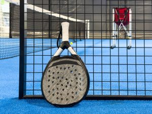 Paddle tennis: Paddel racket and ball in front of an outdoor court