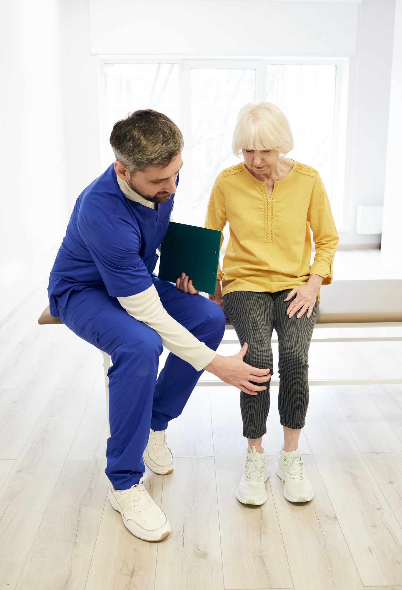 Physiotherapist examining patient's knee. Senior patient with knee injury visit her physiotherapist